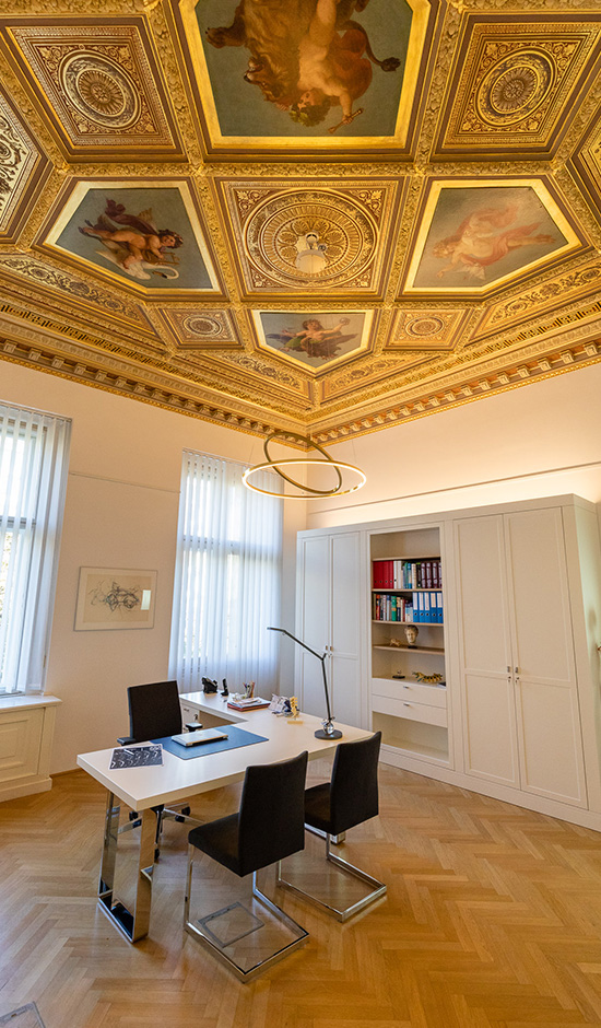 Spine & Specialists Büro mit Schreibtisch, goldener Dekoration und einer mit Gold verzierten Decke mit Deckenmalereien mit Engeln und Gänsen, Adlern, Löwen und Tauben